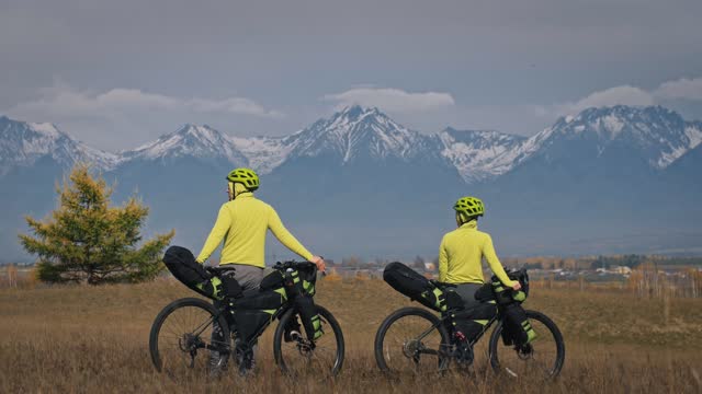 The man and woman travel on mixed terrain cycle touring with bikepacking. The love couple journey with tent in with bicycle bags. Stylish sportswear