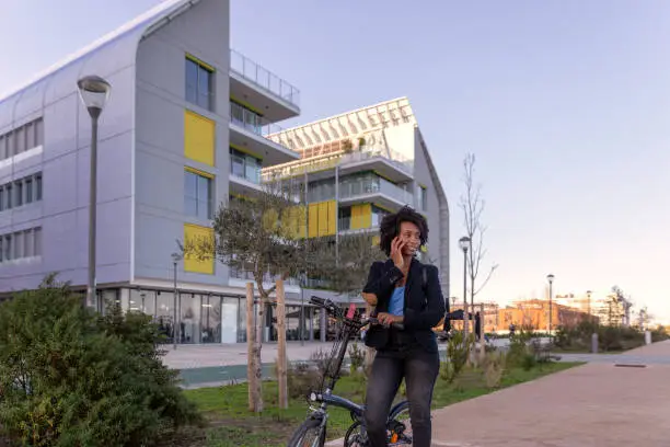 Young black woman casually dressed going to work in a bike