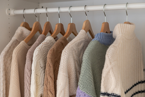 Warm winter beige wool pullover and knitwear and hanging in wardrobe