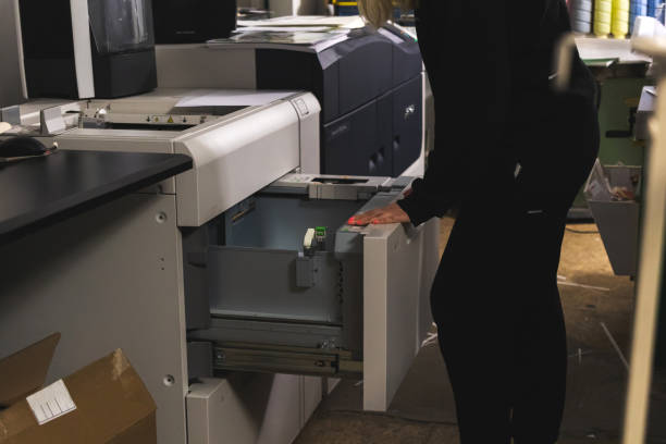istock Worker with modern big print machine in print house. Printing industry concept background 1364829809