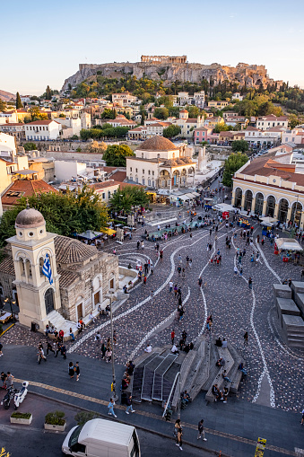 Aerial view of Monastiraki Square, the flea market neighborhood in the old town of Athens. Photo contains many locals and tourists visiting the square. The clustered homes on the hill is known as Plaka. On top of the rock the Parthenon temple of Acropolis famous UNESCO world heritage