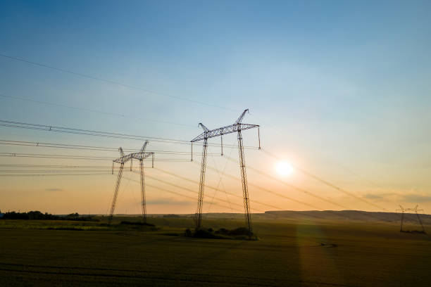 日の出時に電力線を持つ高電圧タワーの暗いシルエット。 - industrial equipment industry growth silhouette ストックフォトと画像