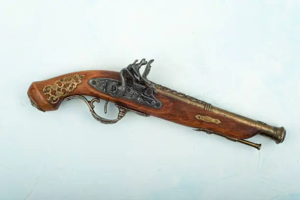 Close-up of an old single-shot pistol with a percussion lock on a wooden background. Copy space.
