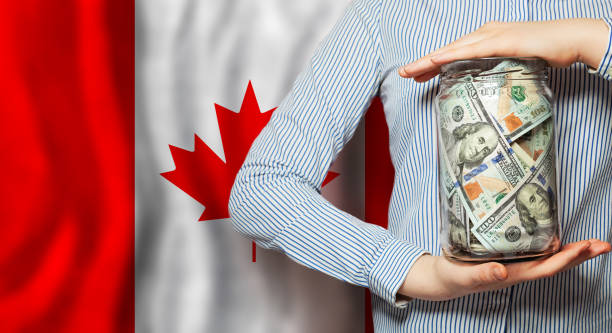 американские доллары наличные деньги в руках на фоне канадского флага - canada investment dollar canadian flag стоковые фото и изображения