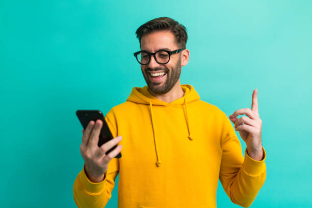 dostałem wiadomość! przystojny mężczyzna z okularami i telefonem komórkowym - men holding smiling young adult zdjęcia i obrazy z banku zdjęć