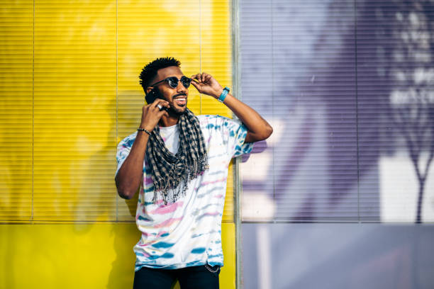 istock Smiling black man leaning against a glass wall using his smartphone 1364845505