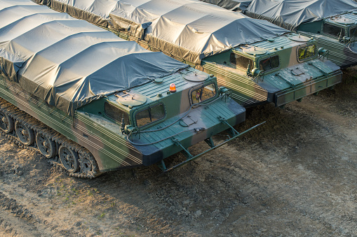 Military amphibious cargo vehicles parked in a row on a muddy battlefield
