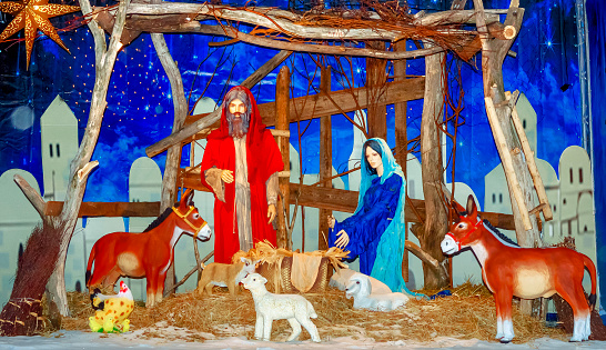 Nativity scene composition reproducing the scene of the Nativity with the use of three-dimensional figures Virgin Mary Baby Jesus Saint Joseph and a donkey with a lamb