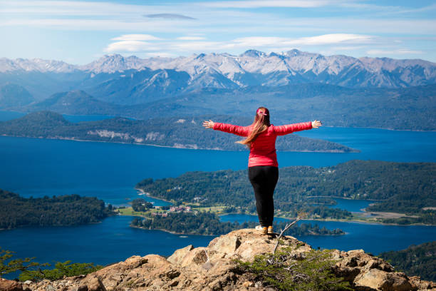 young woman with outstretched arms, on top of a mountain back view of a woman with outstretched arms, on the top of the mountain, surrounded by incredible scenery bariloche stock pictures, royalty-free photos & images