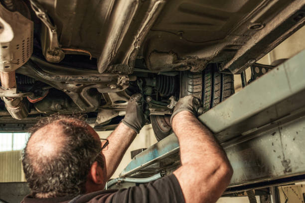 istock Back of a man under a car fixing steering alignment in a garage 1364854678