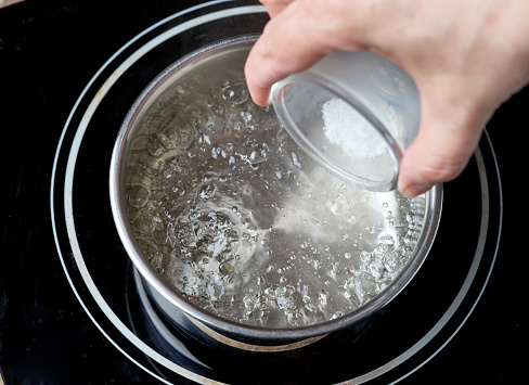 salt is added to boiling water pot on electric induction hob