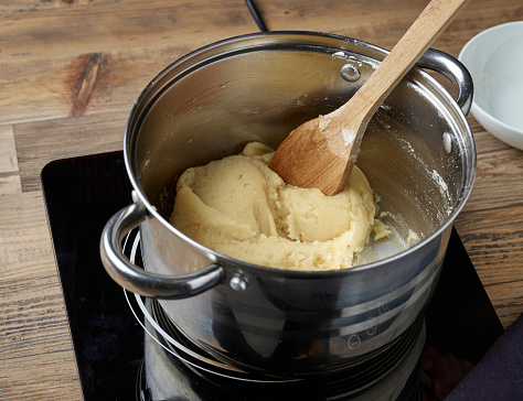 process of making dough for eclairs or cream puffs. pot of dough on electric induction hob