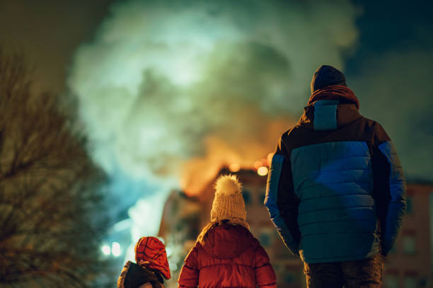 Family losing their home in a fire. Rear view of a father with his children watching their burning building. Fire in the city. Family losing their home in a fire. burning house stock pictures, royalty-free photos & images