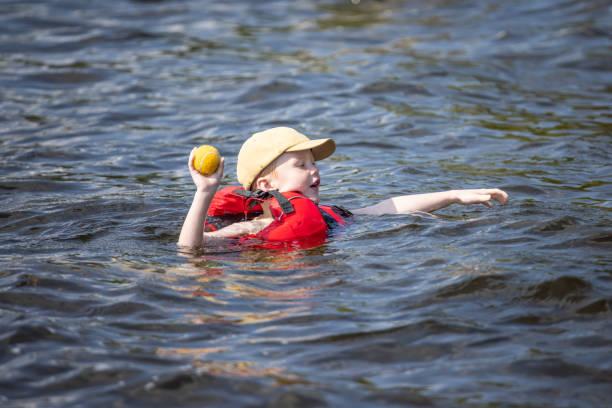 giovane ragazzo che nuota nel lago durante l'estate - life jacket little boys lake jumping foto e immagini stock
