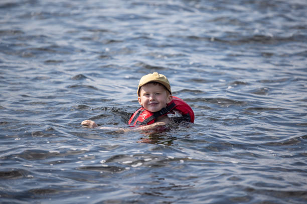 giovane ragazzo che nuota nel lago durante l'estate - life jacket little boys lake jumping foto e immagini stock