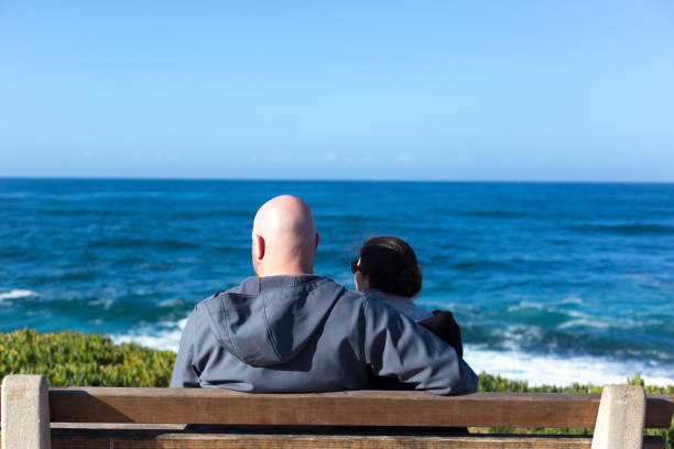 La Jolla, CA: A mature loving couple sitting on a bench overlooking Windansea Beach near downtown La Jolla.