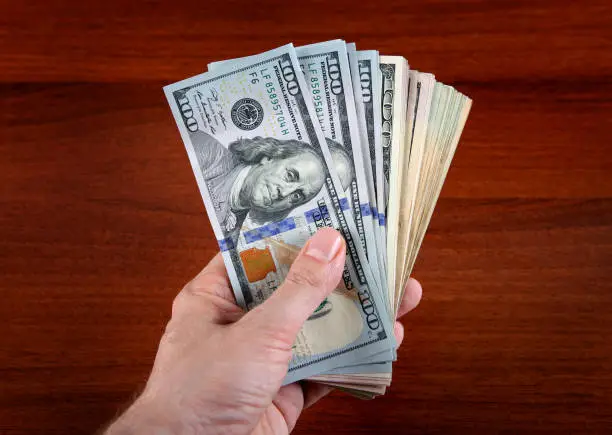 American Dollars in the Hand on the Wooden Table Background