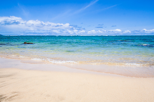 Aerial view of one deck chair, sunbed, lounge, glass of orange juice, flip flops, Lifebuoy, palm tree on sandy beach. Summer and travel concept. Minimalism