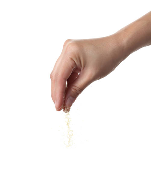 istock Hand sprinkling brown sugar on black background 1364891860