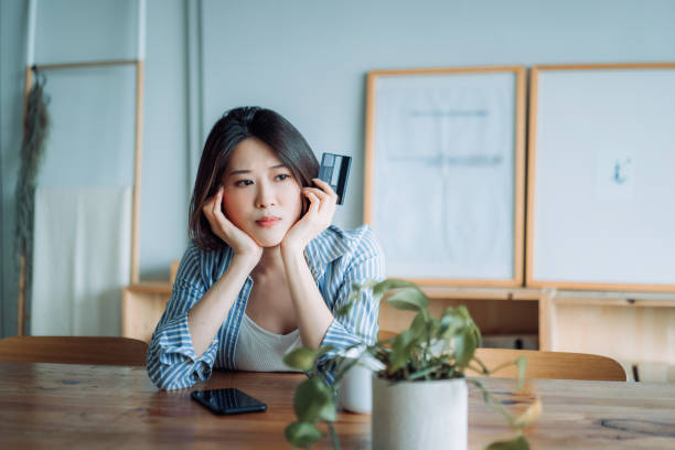 Young Asian woman having problems with her credit card and looking worried. Financial issues, banking, finance, credit card fraud Young Asian woman having problems with her credit card and looking worried. Financial issues, banking, finance, credit card fraud credit card women internet currency stock pictures, royalty-free photos & images