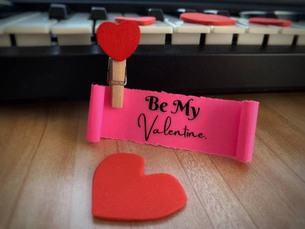 istock Be my Valentine text on torn paper with keyboard, brown table and heart shape background. Valentine's Day concept. 1364896708