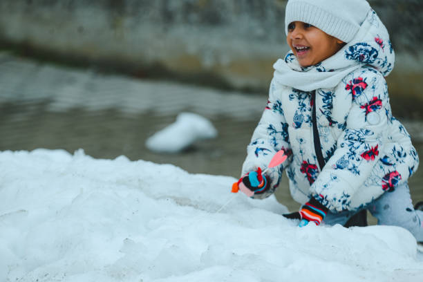 african little girl with hat , scarf and gloves playing in winter outdoors