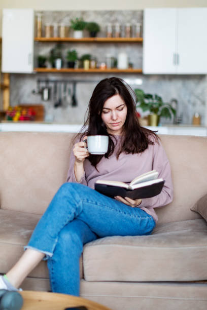 istock Young woman resting at home reading book 1364898759