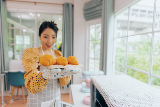 Young Asian female baking croissant bread preparing breakfast, Food and cuisine concept