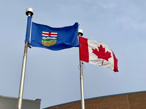 An Alberta Flag with the Canadian flag  during a windy day