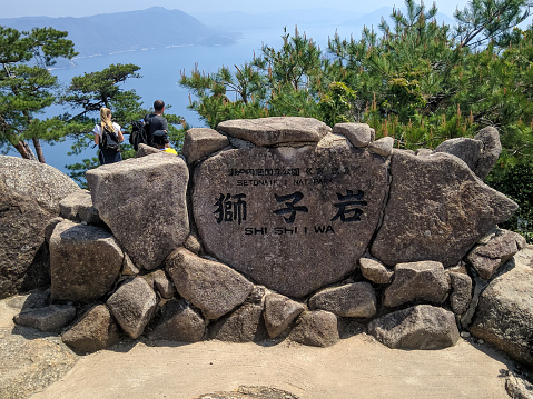 Miyajima, Japan - April 10, 2018: Large stone with the inscription Setonaikai National Park of Miyajima Island. View from Mount Misen, height 535 meters, to the bay of the city of Hiroshima.