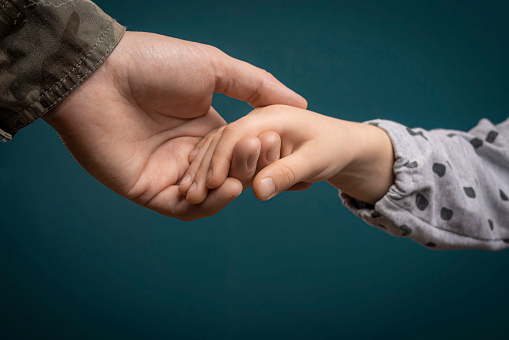A soldier's hand holds a child's hand in close-up. My father is a military man. A soldier and a child. Father's love