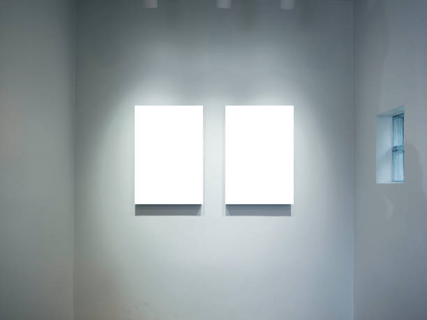 istock Two mockup vertical rectangle painting frames hanging on white wall background with spotlights. Blank white canvas frame with empty space in gallery, minimal style. 1364902535