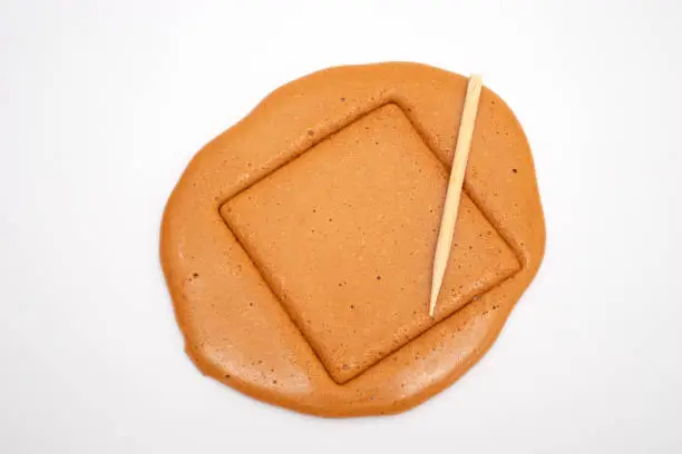 Photo of Korean Dalgona sugar candy cookie with a metal needle