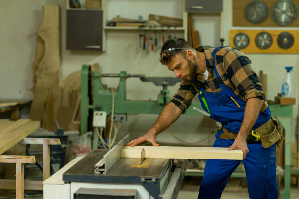 istock Handsome carpenter preparing, measures and cutting boards on cutting machine 1364907846