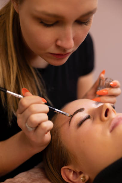 istock Cosmetologist Applying Dye On Female Client's Eyebrow 1364911291
