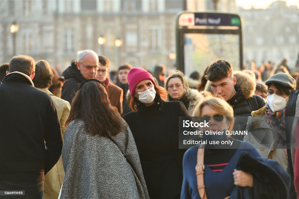 People wearing mask in a street of Paris, France. Paris, France-01 15 2022: People wearing protective face masks in a street of Paris, France during the global coronavirus epidemic. Coronavirus Stock Photo