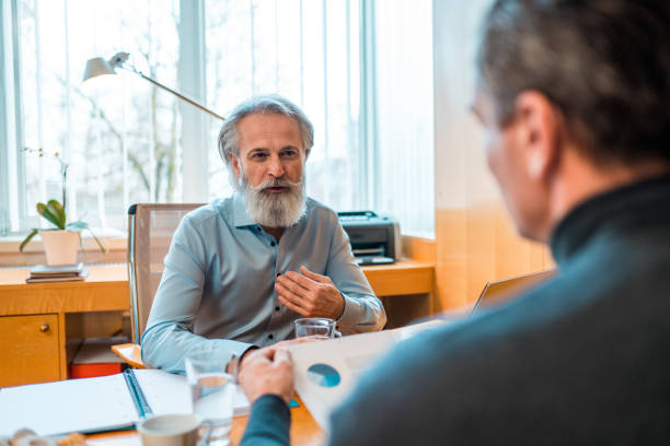 istock Mature Financial Advisor Explaining Graphs to Mature Male Client in an Office 1364912404