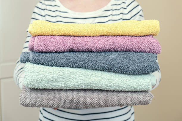 istock Woman holds a stack of clean terry towels. Folding clean linen 1364913911