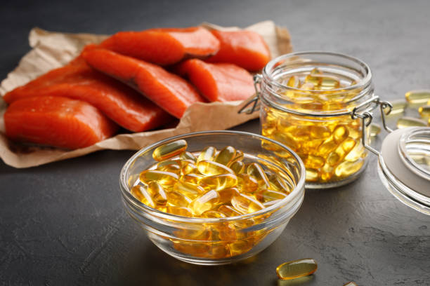 capsules d’oméga 3 et poisson rouge saumon - vitamin d capsule fish oil yellow photos et images de collection
