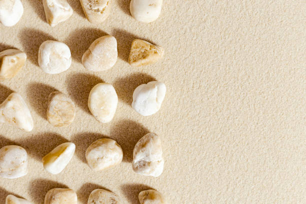 istock Aesthetic minimal pattern with pebble stones on fine sand background. Top view on natural stone neutral yellow beige pastel colored image 1364916540