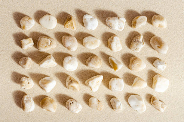 istock Aesthetic minimal pattern with set of pebble stones on fine sand background. Square composition from natural stone neutral beige color 1364916542