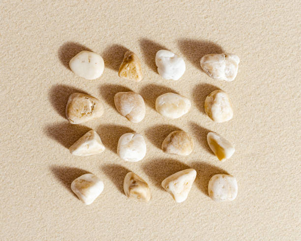 istock Aesthetic minimal pattern with set of pebble stones on fine sand background. Square composition from natural stone neutral beige color 1364916544