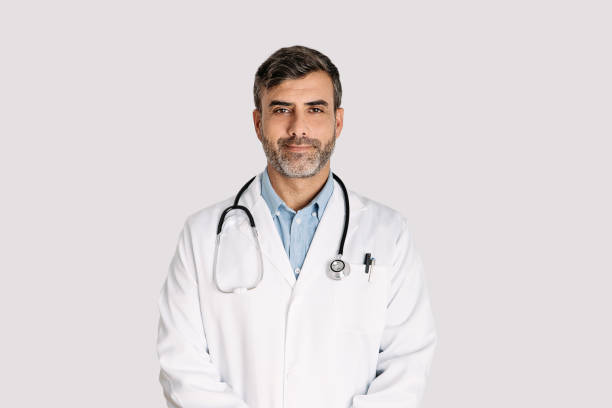 Handsome doctor smiling and standing on white background Front view of handsome doctor smiling and standing on white background middle eastern clothes stock pictures, royalty-free photos & images