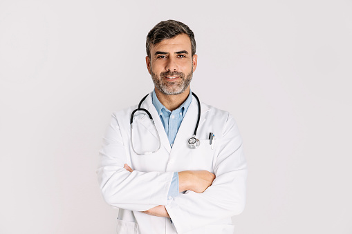 Front view of handsome doctor smiling and standing on white background