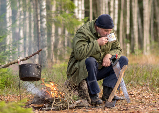 istock a forester in the forest drinks tea at rest, blurred forest background, bonfire with a pot over it, in the autumn 1364920173