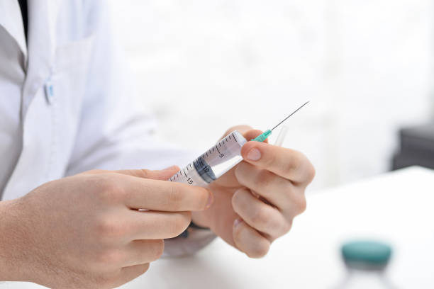 istock A doctor holding an injection syringe in his hand on white office 1364920943