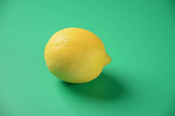 istock Lemon isolated on green background. The lemon is both a small evergreen tree, native to Asia, and the tree's oval yellow fruit 1364921102