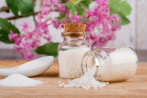 Homeopathy globules in bottles on a table with spoon and powder