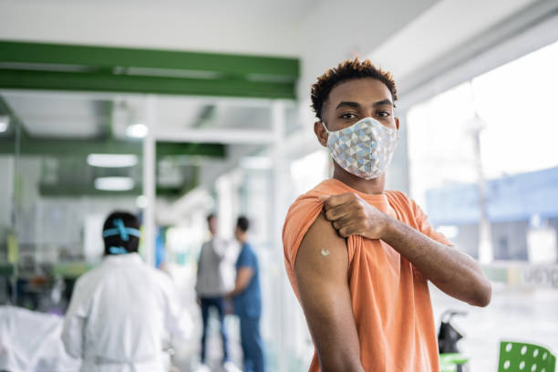 Portrait of a young man showing his arm after vaccination Portrait of a young man showing his arm after vaccination rolled up sleeves stock pictures, royalty-free photos & images