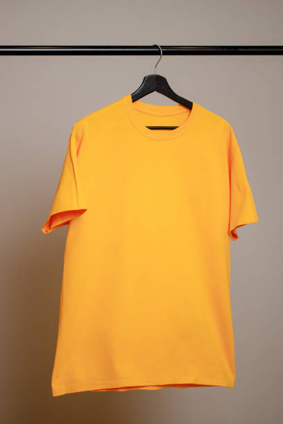 istock Empty yellow T-shirt hanging on a hanger on a gray background. Mock up for design 1364925280